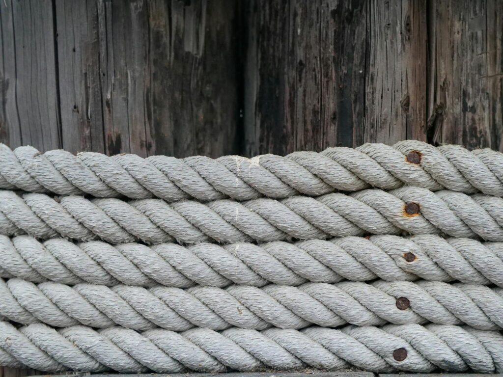 Detailed view of coiled nautical ropes against a rustic wooden background, emphasizing texture.